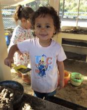 Child standing in playhouse with mud